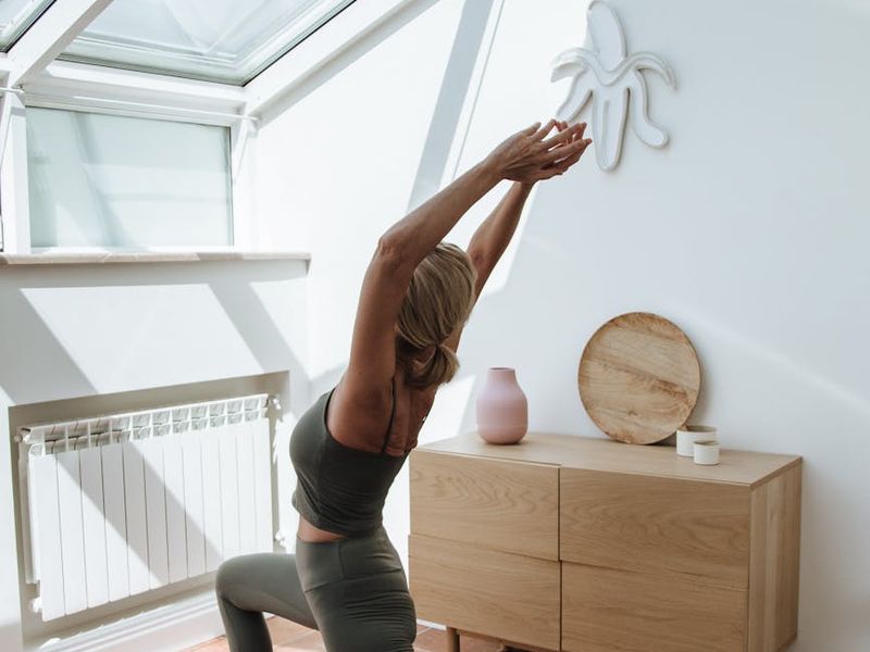 Woman performing a yoga stretch in a bright, clean room.